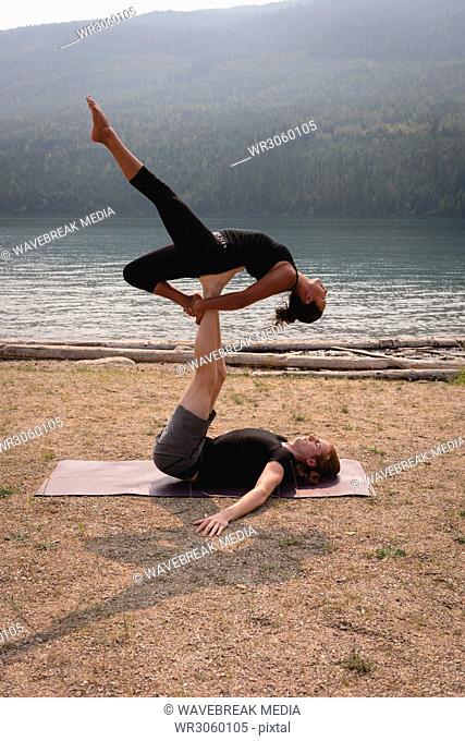 Fit couple practicing acro yoga in a lush green ground