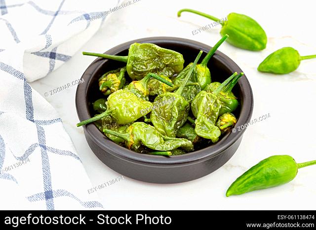 Cooked Padron peppers in a a bowl on marble table. Traditional Spanish appetizer