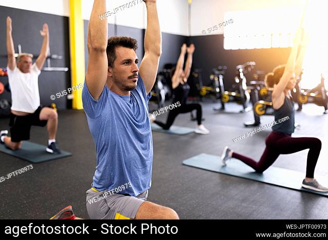 Athletes with arms raised exercising in gym