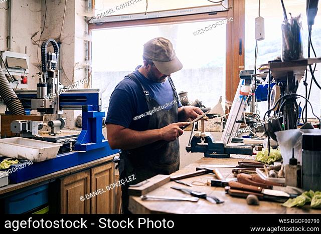 Craftsman making knives in his workshop examining the blade