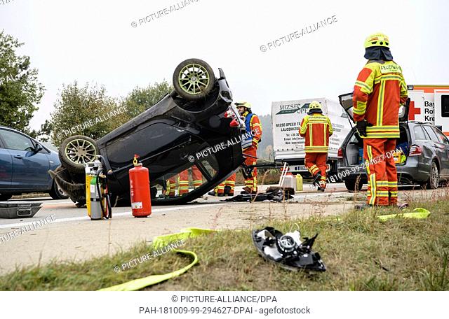 09 October 2018, Bavaria, Bachl: Firefighters work around an accidental station wagon and an upside-down small car on the 93 motorway just behind the motorway...