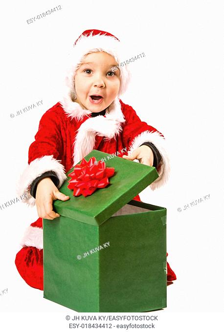 Adorable 5 year old boy wearing Santa Claus costume, he opens Christmas gift, white background