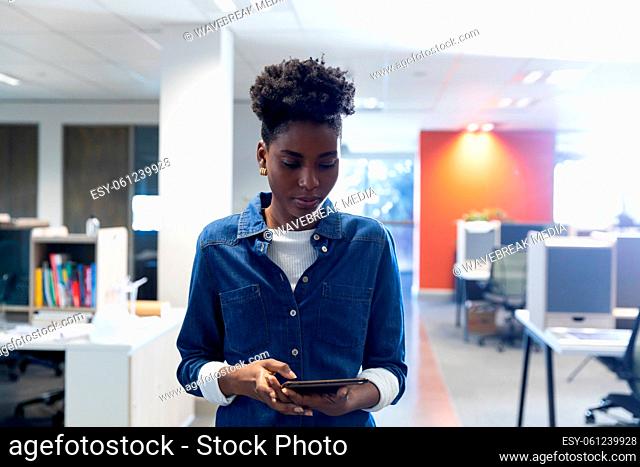Confident african american businesswoman using digital tablet standing at modern workplace