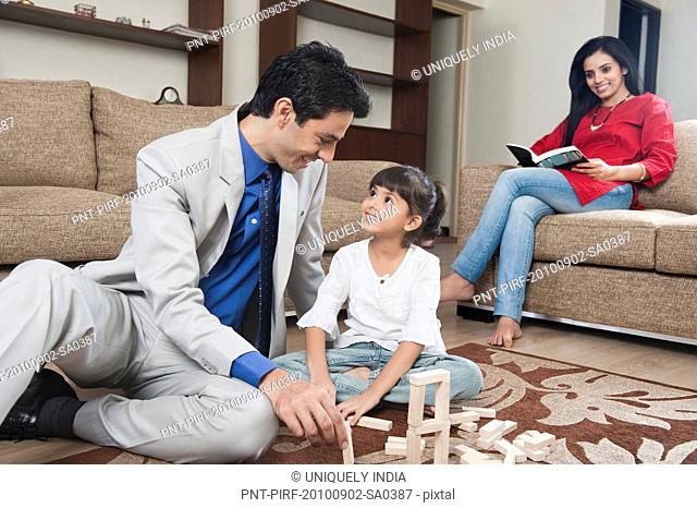Woman looking at her daughter playing Jenga with her father