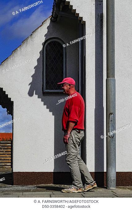 Hirtshals, Denmark A man casually walks by the shadow of a building detail