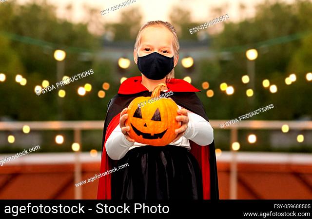girl in halloween costume and mask with pumpkin