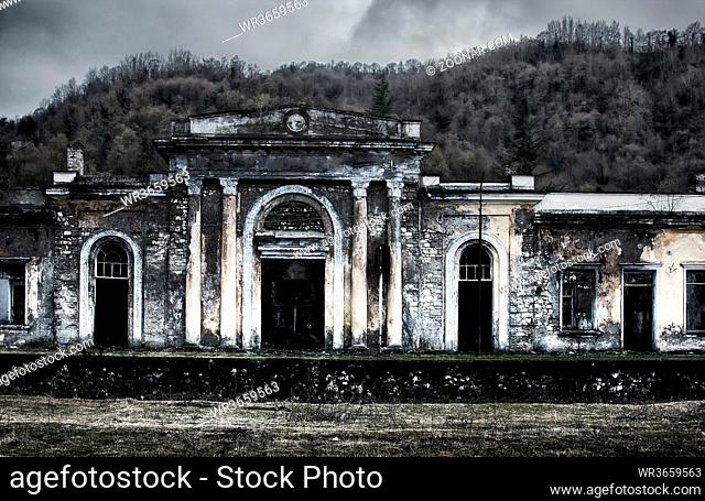 old mansion with pilasters and circular Windows on the West Bank of the Black sea. Winter forest mountains in the background. Picturesque ruins
