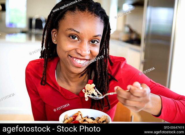 A Young Woman in a Pink Shirt Eating Bran Flake Cereal