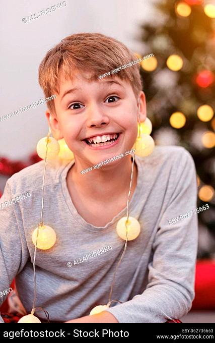 Portrait of a Christmas boy. Cute smiling child having fun with christmas balls looking at camera