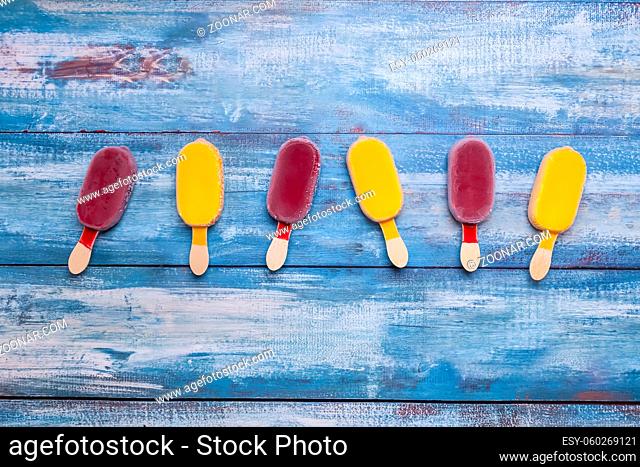 Fruit ice cream stick looking fresh to eat placed on a blue vintage wooden background