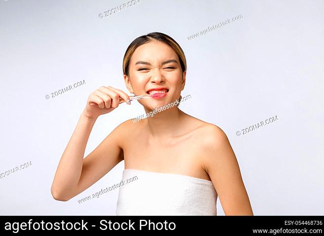 Beautiful young woman on white isolated background holds a toothbrush, Asian