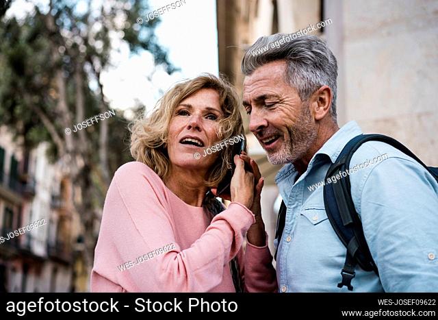 Mature woman talking on smart phone by man