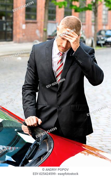 Upset Driver Looking At Parking Ticket On Car Windscreen