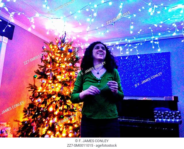 A woman decorates a room with holiday lights