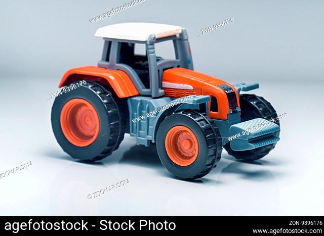 Small red toy tractor on light background, shallow depth of field