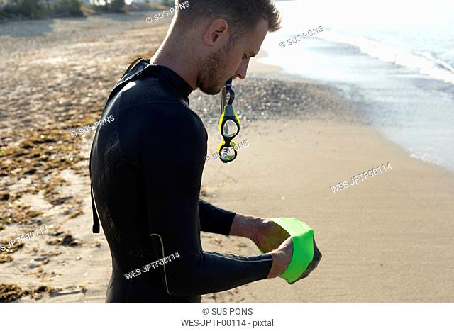 Triathlete putting on swimming goggles, getting ready for an ocean swim