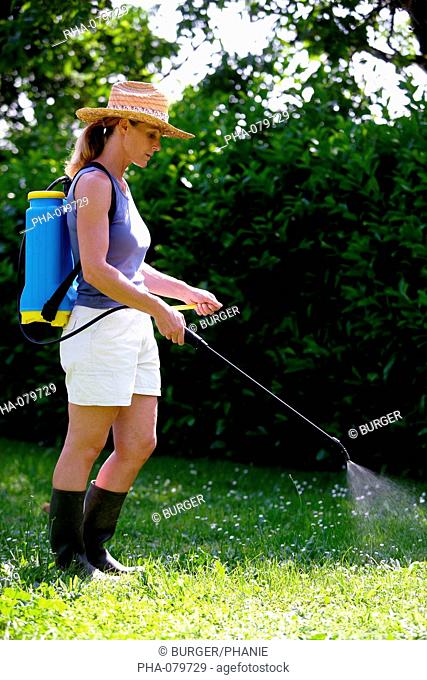 Woman spraying weed killer of pesticide in the garden