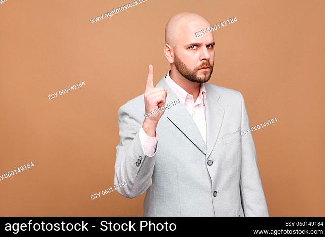 Hey you. Portrait of serious handsome middle aged bald bearded boss businessman in classic gray suit standing and looking at camera, warning