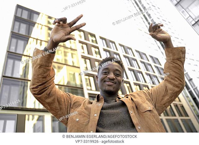 positive African man with arms up in business district of city, in Frankfurt, Germany