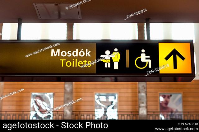 Toilet sign on wall glowing in yellow