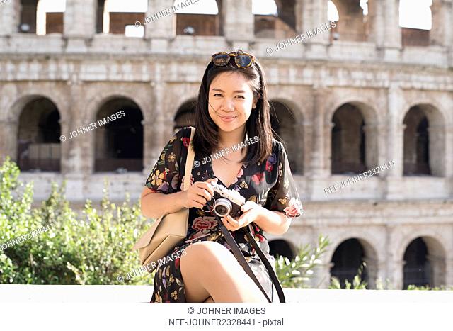 Young woman sitting in front of Coliseum, Rome, Italy