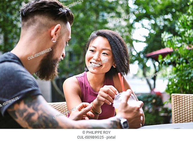 Multi ethnic hipster couple talking at sidewalk cafe, Shanghai French Concession, Shanghai, China