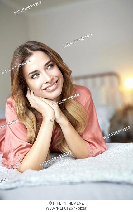 Smiling young woman in dressing gown lying in bed
