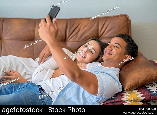 Couple, young, in love, lying on sofa, cell phone, holding