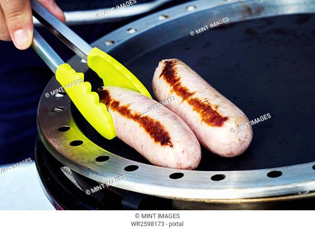 Close up of a sausage being fried on a camping stove