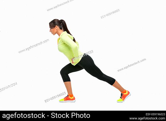 Young beautiful fit woman stretching legs. Isolated over white background. Copy space