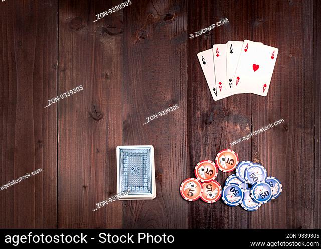 Chips and Four aces vintage poker game playing cards on a weathered wood table, view from above