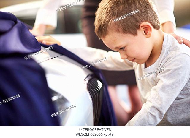 Boy at car dealer unveiling tarpaulin
