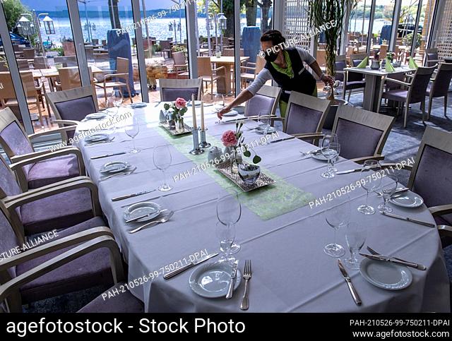 26 May 2021, Mecklenburg-Western Pomerania, Plau am See: A waitress sets a table in the restaurant at the Seehotel on Lake Plauer See