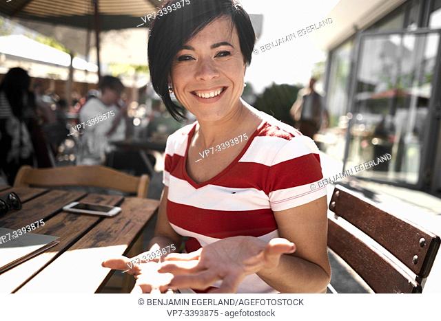 happy woman in outdoor restaurant, at Herrenchiemsee, Chiemsee, Bavaria, Germany