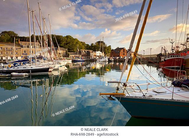 Low morning light and sailing yacht reflections at Padstow Harbour, Cornwall, England, United Kingdom, Europe