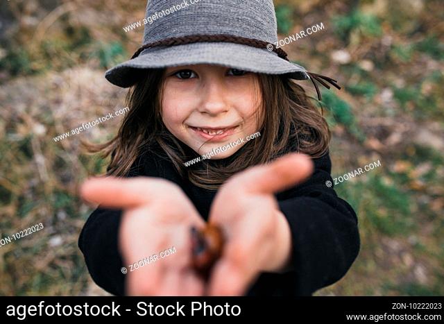 little girl in a black coat and hat posing in autumn park