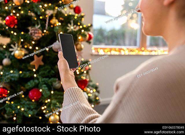 close up of woman with smartphone on christmas