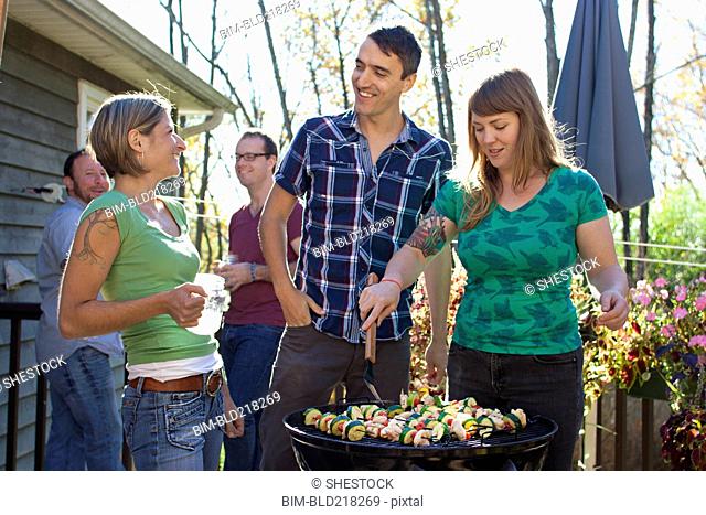 Friends grilling vegetables in backyard