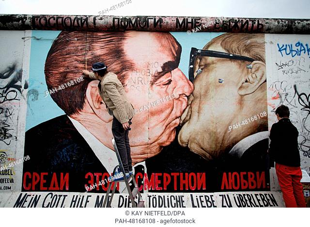 Artist Dimitri Vrubel (L) and son Artjom clean the graffiti painting of the socialist fraternal kiss at the East Side Gallery in Berlin, Germany, 27 April 2014