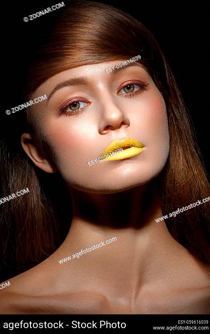 beautiful young woman with yellow lips makeup and long straight glossy hair. beauty shot black background. copy space