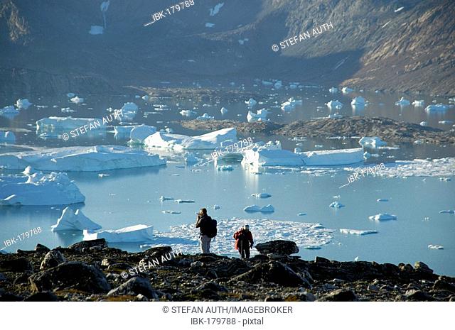 People in front of fjord with icebergs and mountains Nagtivit Kangertivat Fjord Eastgreenland