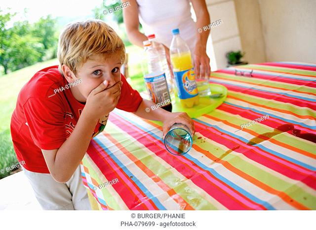 Mischiefly boy spilling glass on the table
