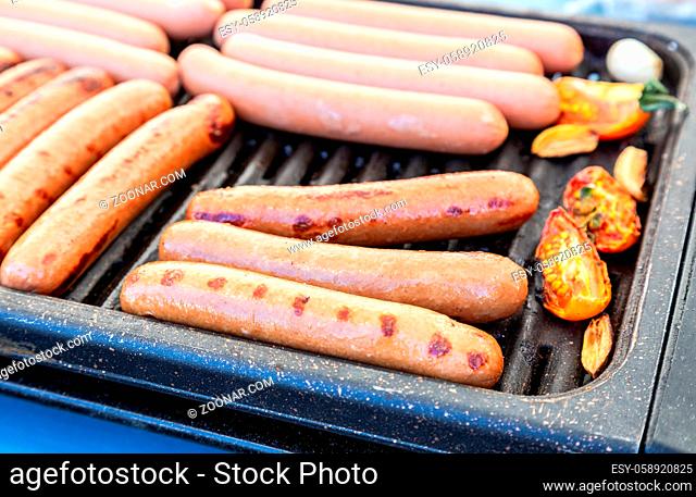 Delicious sausages on a metal grid grilling over hot coals for a picnic lunch on a summer vacation