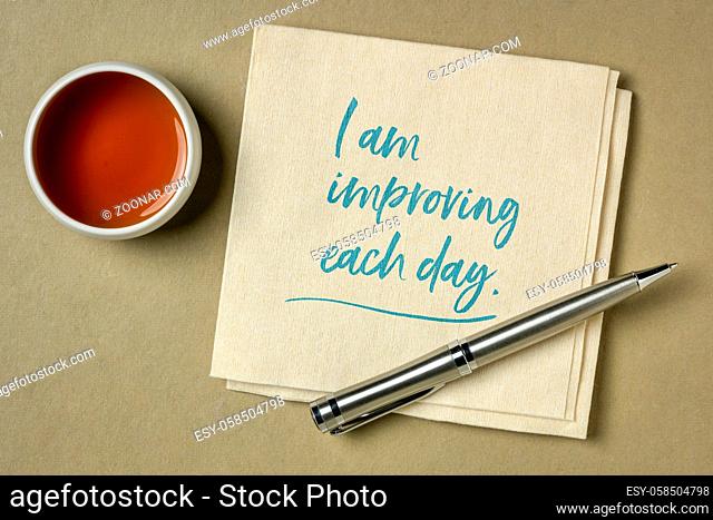 I am improving each day - positive affrimation, handwriting on a napkin with a cup of tea, self improvement and personal development concept