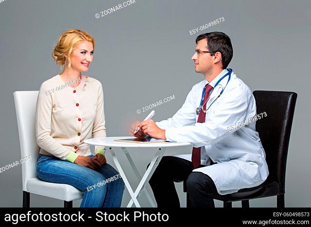 handsome doctor in white coat talking to beautiful woman patient. studio shot. copy space