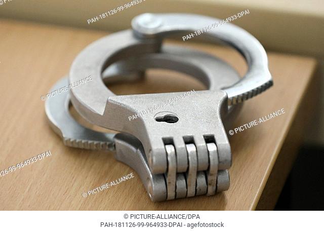 26 November 2018, Mecklenburg-Western Pomerania, Rostock: The defendants' handcuffs are lying on a table in the courtroom of the Regional Court before the...