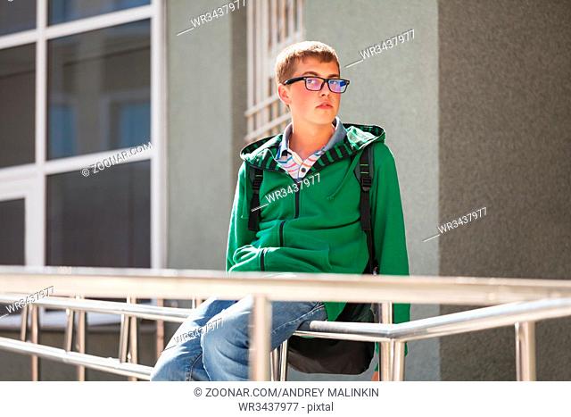 Teen boy in a hoodie against school building
