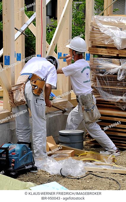 Assembly of a modern prefabricated house in light wooden framework construction, workmen with tools in waistbelts, Iwakura near Kyoto, Japan, Asia