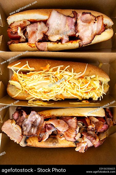 American hot dog with different flavors, with cheese and crispy onions on a white table in a minimalist style. Fast food, takeaway food, food for motorists