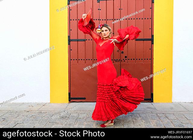 Female artist with hand fan dancing in front of door